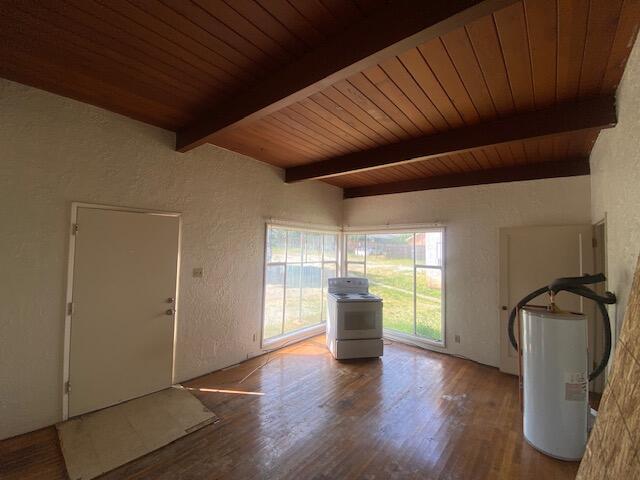 foyer entrance with gas water heater, washer / clothes dryer, beam ceiling, a textured wall, and wood finished floors