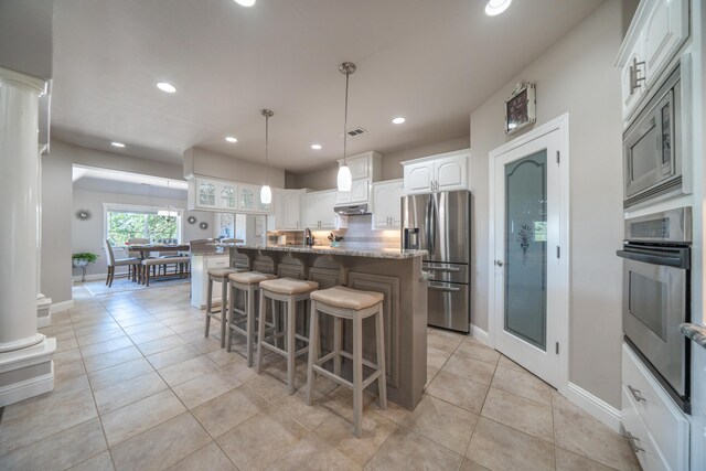 kitchen with stainless steel appliances, a kitchen breakfast bar, white cabinetry, recessed lighting, and a center island with sink
