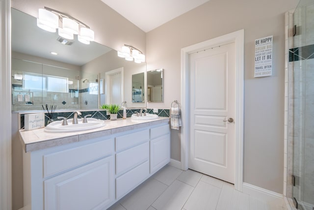 bathroom featuring a stall shower, double vanity, tile patterned flooring, and baseboards