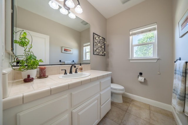 bathroom featuring baseboards, toilet, vanity, and tile patterned floors