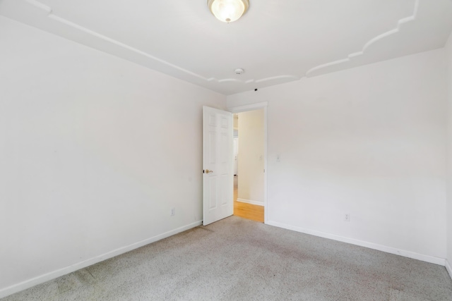 carpeted spare room featuring baseboards