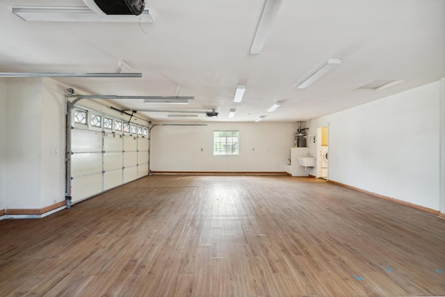 garage with baseboards, a sink, a garage door opener, and water heater