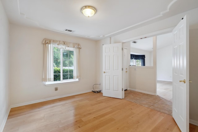 spare room featuring plenty of natural light, light wood-style floors, and baseboards