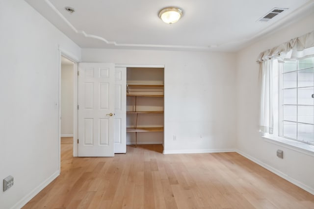 unfurnished bedroom featuring light wood-style flooring, a closet, and baseboards