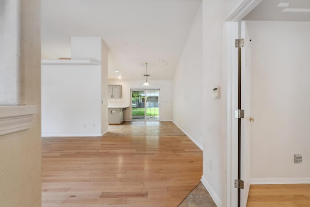 hall featuring light wood-style flooring and baseboards