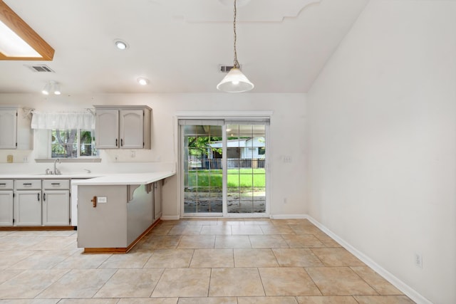 kitchen with plenty of natural light, light countertops, a peninsula, decorative light fixtures, and recessed lighting