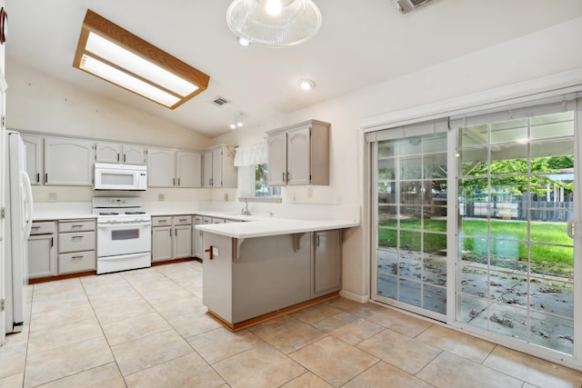 kitchen with white appliances, vaulted ceiling, a peninsula, light countertops, and a kitchen bar