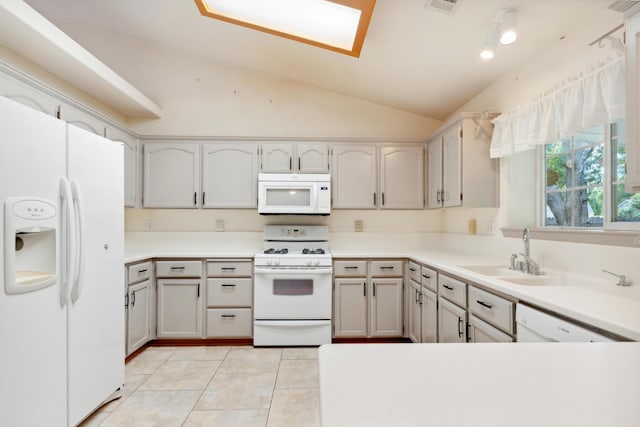 kitchen with white appliances, a sink, lofted ceiling, light tile patterned floors, and light countertops