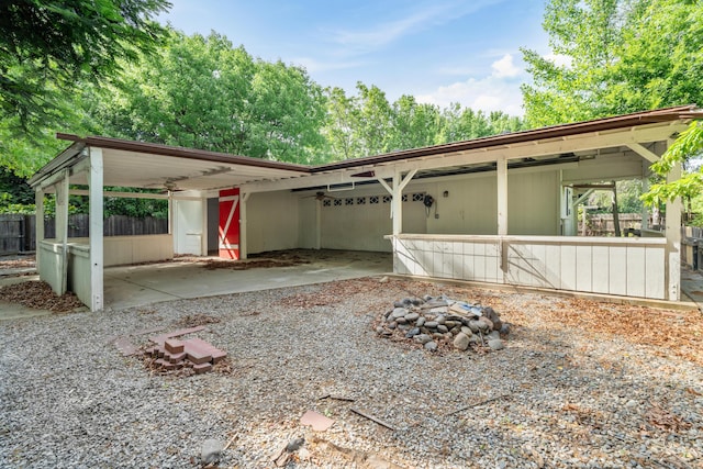 view of side of property with fence, an outdoor fire pit, and a carport