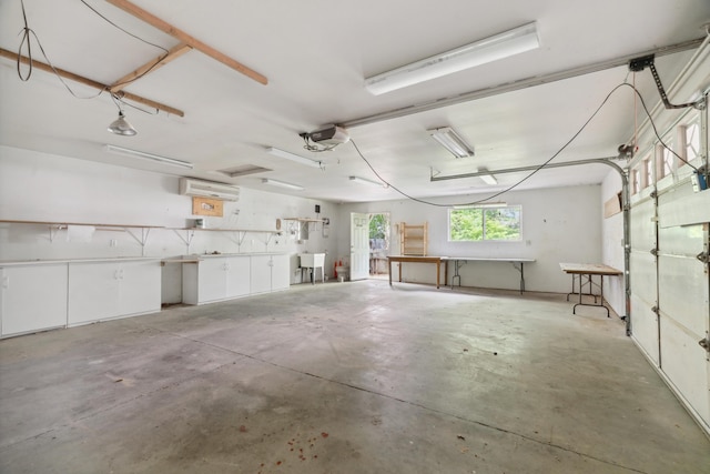 garage featuring a wall mounted air conditioner, a garage door opener, and a sink