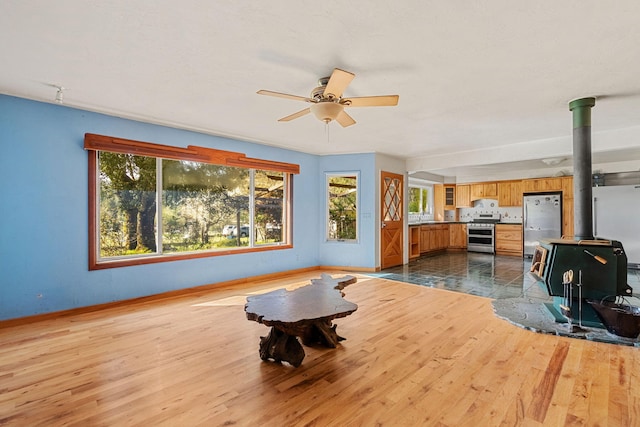 8686 Bell Springs Rd, Garberville, CA 95542 - living area featuring a wood stove, healthy amount of natural light, dark wood-style flooring, and ceiling fan