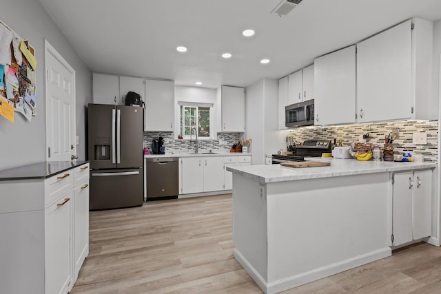 2350 Christian Ave, Redding, CA 96002 - kitchen with appliances with stainless steel finishes, a sink, light wood-type flooring, backsplash, and white cabinetry