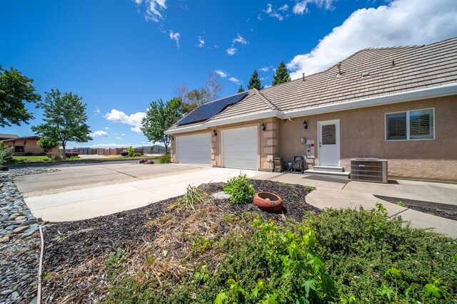 831 Santa Cruz Dr, Redding, CA 96003 - rear view of property featuring stucco siding, solar panels, driveway, central AC unit, and a garage
