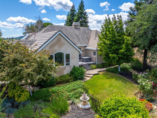831 Santa Cruz Dr, Redding, CA 96003 - back of house with stucco siding, a wooden deck, a lawn, a tiled roof, and a chimney