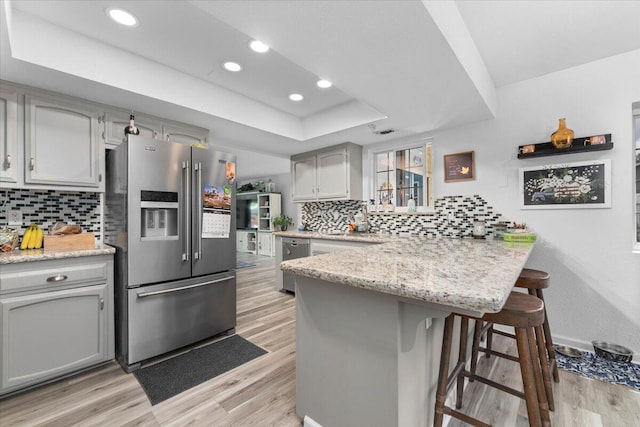 7597 Terra Linda Way, Redding, CA 96003 - kitchen with appliances with stainless steel finishes, a peninsula, light wood-style flooring, a kitchen breakfast bar, and gray cabinetry