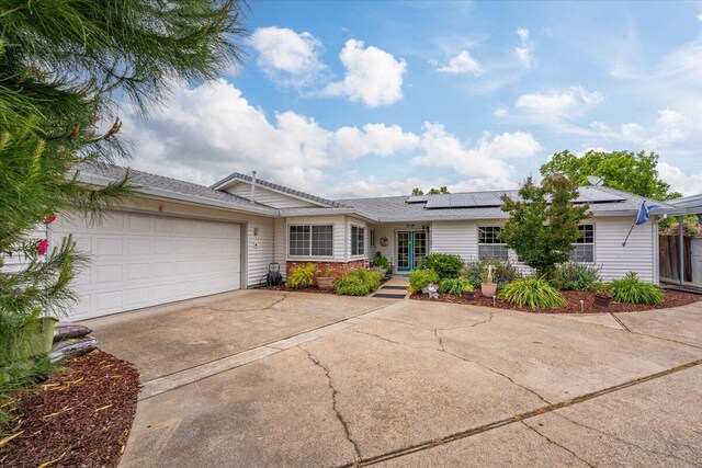 7597 Terra Linda Way, Redding, CA 96003 - ranch-style house featuring driveway, an attached garage, and roof mounted solar panels