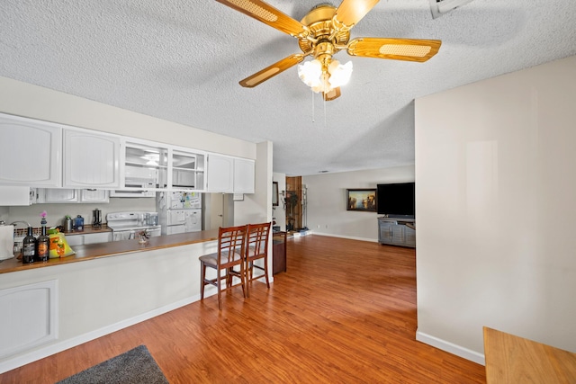 1836 Del Mar Ave, Redding, CA 96003 - kitchen with white electric stove, a textured ceiling, wood finished floors, white cabinets, and a ceiling fan