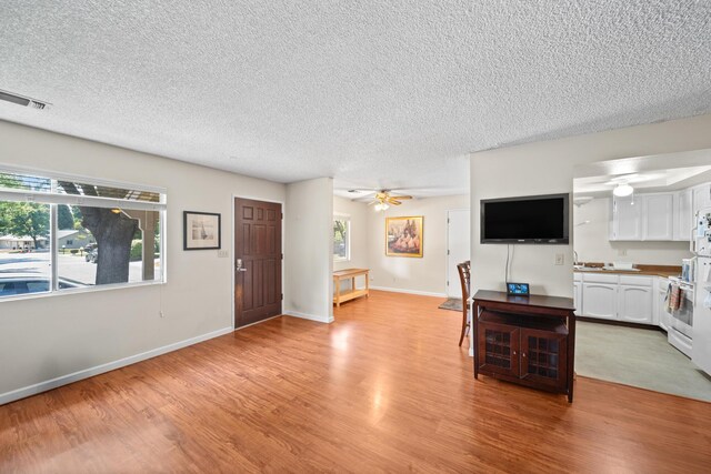 1836 Del Mar Ave, Redding, CA 96003 - living area featuring light wood-type flooring, a textured ceiling, healthy amount of natural light, and ceiling fan