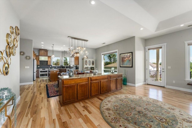 1235 Chandon Ct, Redding, CA 96003 - kitchen with freestanding refrigerator, range with two ovens, light wood-style floors, brown cabinetry, and a large island