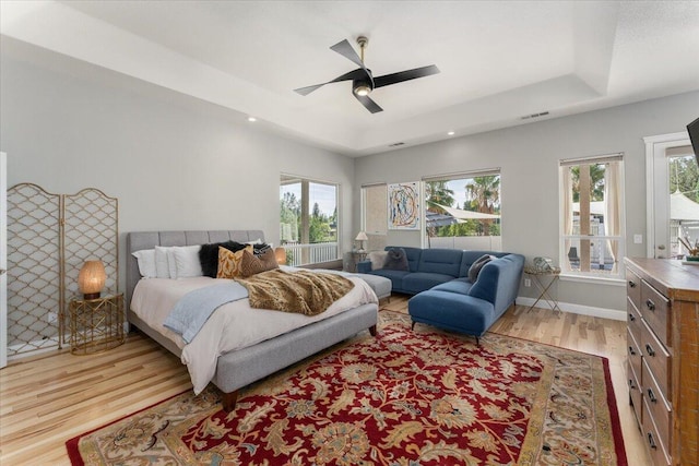 1235 Chandon Ct, Redding, CA 96003 - bedroom with light wood-type flooring, multiple windows, a tray ceiling, recessed lighting, and ceiling fan