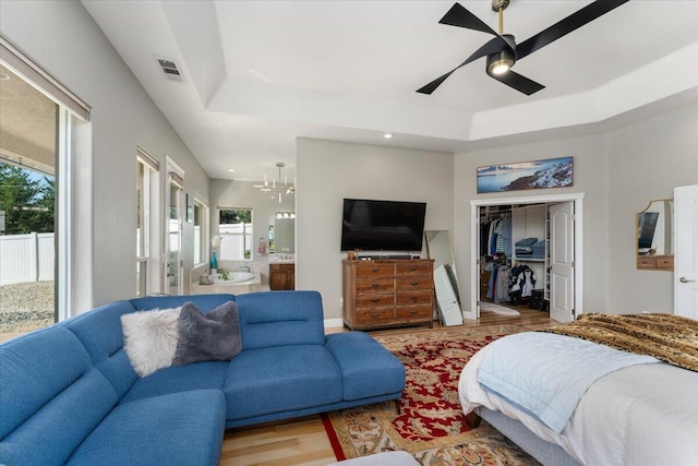 1235 Chandon Ct, Redding, CA 96003 - bedroom featuring a raised ceiling, wood finished floors, a chandelier, ensuite bath, and a spacious closet