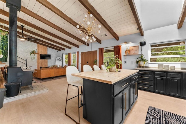 19697 Old Indian Trl, Redding, CA 96003 - kitchen featuring a wood stove, dark cabinets, a kitchen breakfast bar, wooden counters, and light wood-style floors
