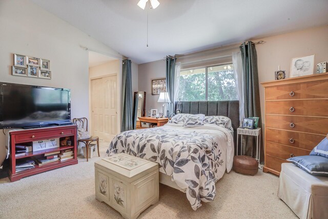 bedroom with light carpet, lofted ceiling, a closet, and a ceiling fan