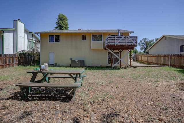 rear view of house featuring a fenced backyard, central AC, and a wooden deck