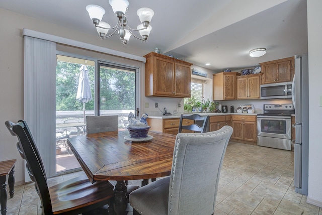 dining space featuring plenty of natural light, a chandelier, lofted ceiling, and light stone finish floors