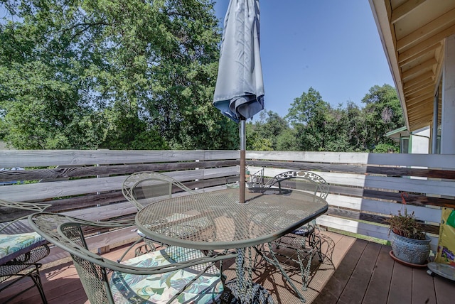 wooden deck with outdoor dining area and view of wooded area
