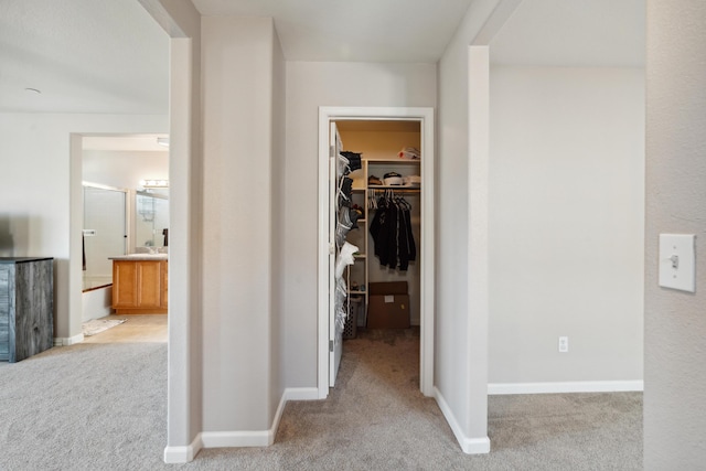 hall featuring carpet flooring and baseboards