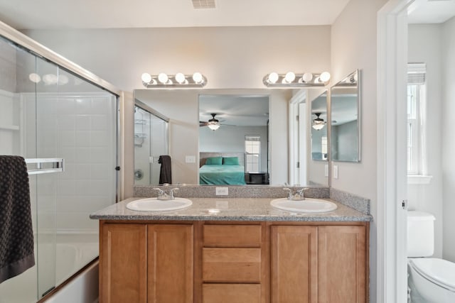 full bathroom with ceiling fan, ensuite bathroom, double vanity, toilet, and shower / bath combination with glass door