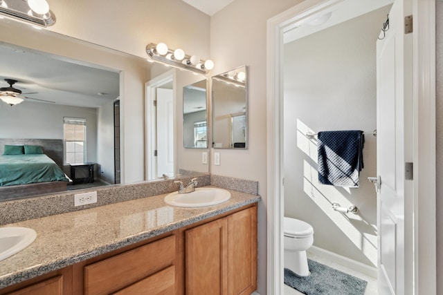full bath featuring connected bathroom, toilet, double vanity, ceiling fan, and tile patterned flooring