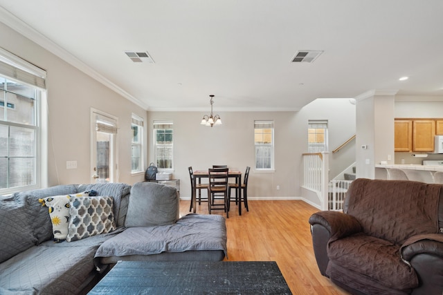 living room with a chandelier, plenty of natural light, stairway, light wood-style floors, and ornamental molding