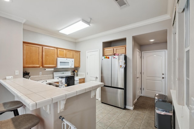kitchen with white appliances, a peninsula, a breakfast bar area, ornamental molding, and light tile patterned flooring