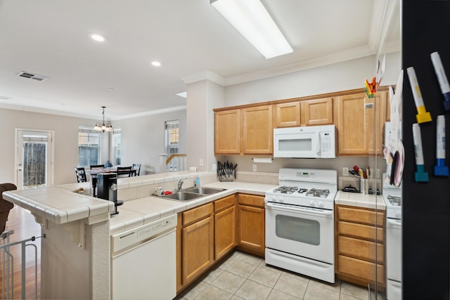 kitchen with white appliances, a peninsula, tile counters, ornamental molding, and a chandelier