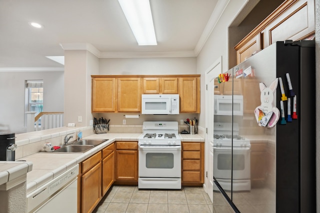kitchen with white appliances, a sink, tile countertops, light tile patterned floors, and crown molding