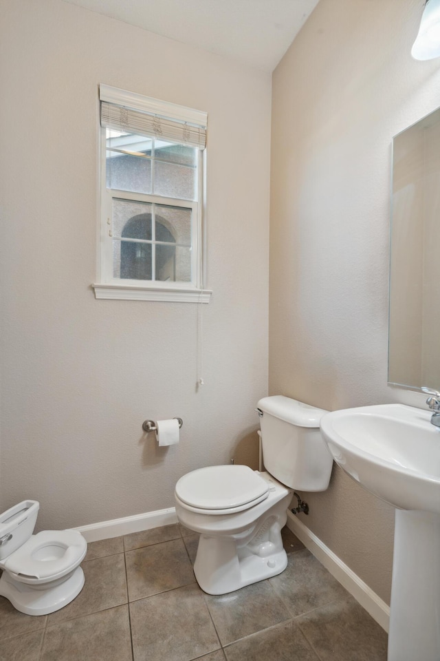 bathroom featuring toilet, baseboards, tile patterned floors, and a sink