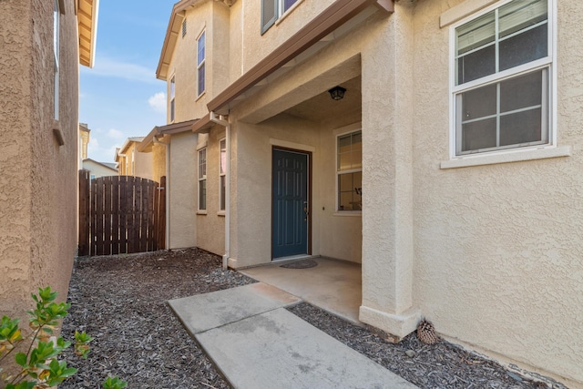 entrance to property with stucco siding and fence