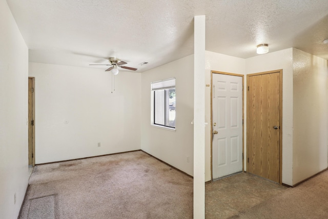 entrance foyer featuring ceiling fan, light carpet, a textured ceiling, and baseboards