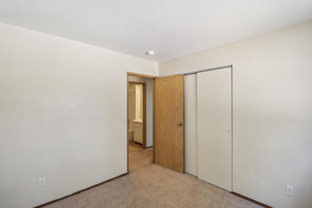 unfurnished bedroom with a closet and light carpet