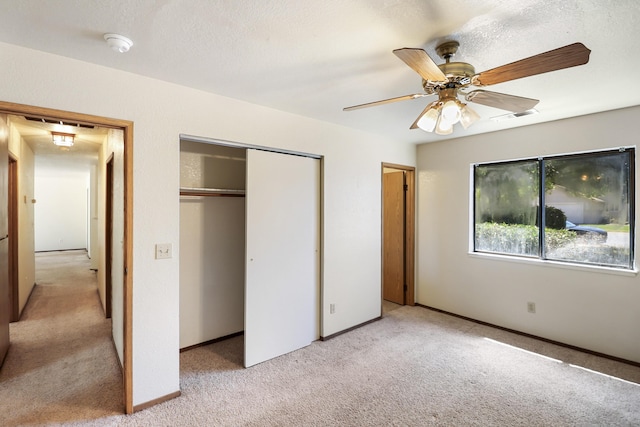 unfurnished bedroom featuring light carpet, a closet, baseboards, and a ceiling fan