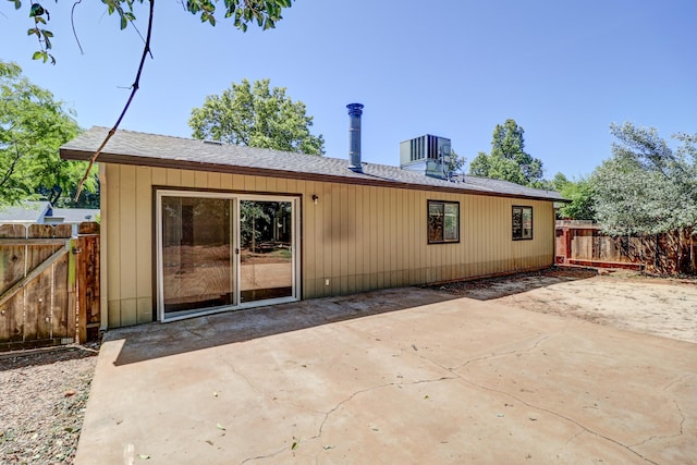 rear view of house with fence, a shingled roof, a patio area, and central AC