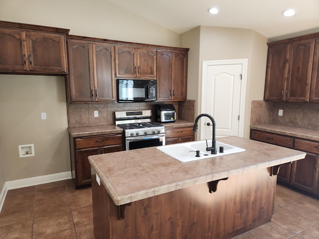 3621 Sacramento Dr, Redding, CA 96001 - kitchen featuring black microwave, stainless steel range with gas cooktop, decorative backsplash, light countertops, and a kitchen bar