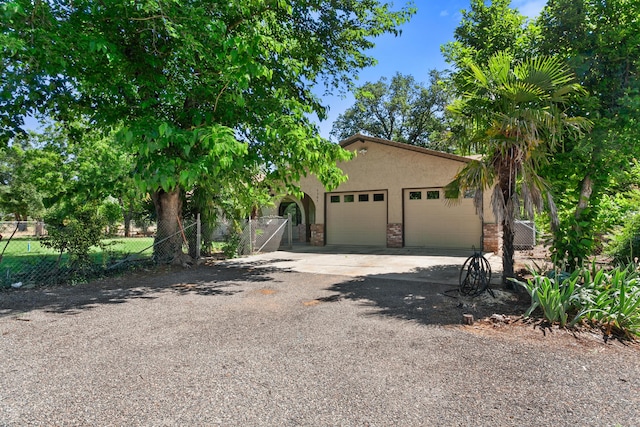 5165 Rancho Vista Way, Redding, CA 96002 - view of property hidden behind natural elements with fence, a garage, concrete driveway, and stucco siding