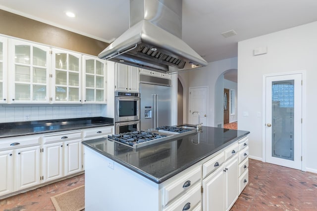 17917 Lakeshore Dr, Weed, CA 96094 - kitchen with island exhaust hood, stainless steel appliances, arched walkways, glass insert cabinets, and white cabinetry