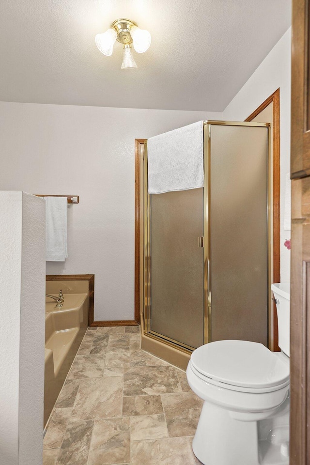 bathroom featuring toilet, a shower stall, a garden tub, stone finish floors, and baseboards