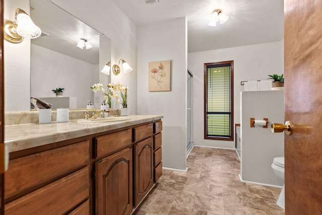 bathroom with a stall shower, toilet, vanity, and baseboards