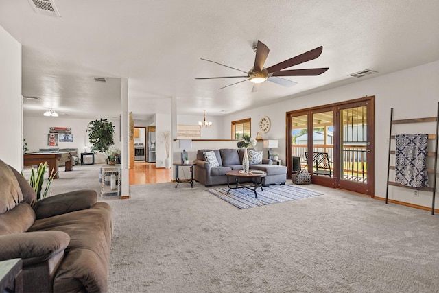 living area featuring a ceiling fan, carpet floors, and a chandelier