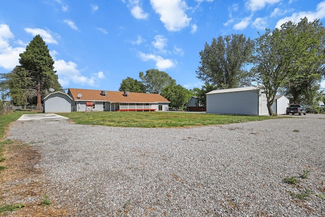 view of front of house featuring driveway, an outdoor structure, and a front lawn
